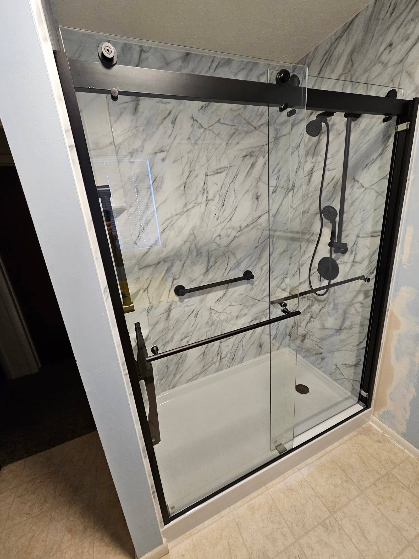Marble shower with black sliding glass door, a real KVB project