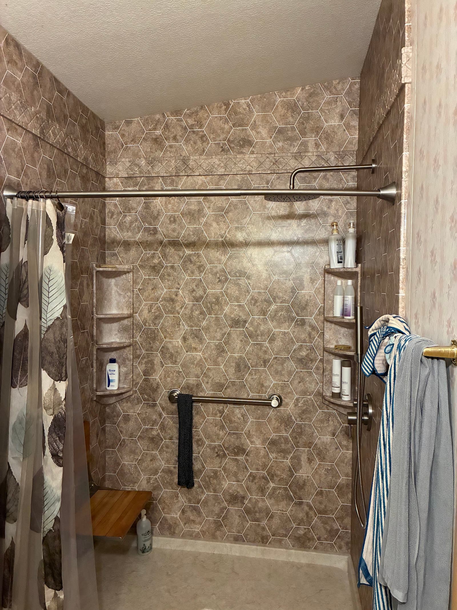 Warm stone-pattern shower with chrome grab bars